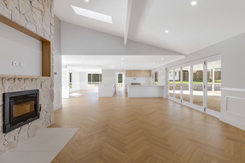 Open-plan living room with stone fireplace and herringbone timber floor