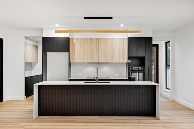 Kitchen island with black cabinetry and timber overheads