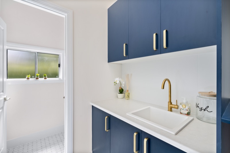 Laundry with navy joinery and brass tapware